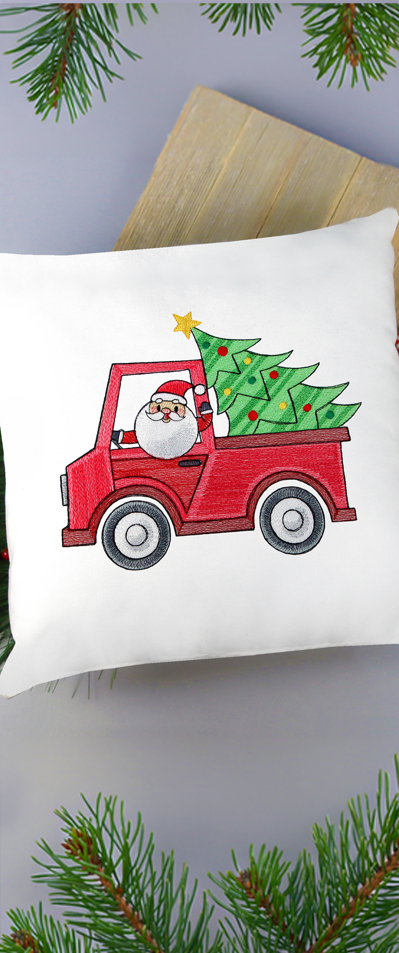 machine embroidery design of a Santa driving a red pickup truck with a stylized Christmas tree in the back, stitched onto a white pillow.