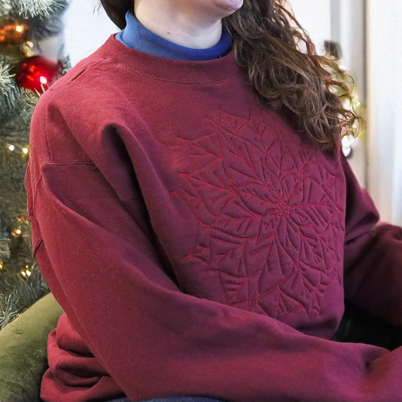 A person wearing a machine embroidery poinsettia design on a red sweatshirt