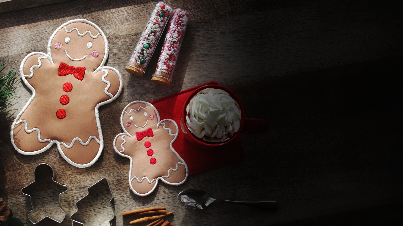  Gingerbread cookie trivet machine embroidery designs on a wooden surface with a mug of hot chocolate.