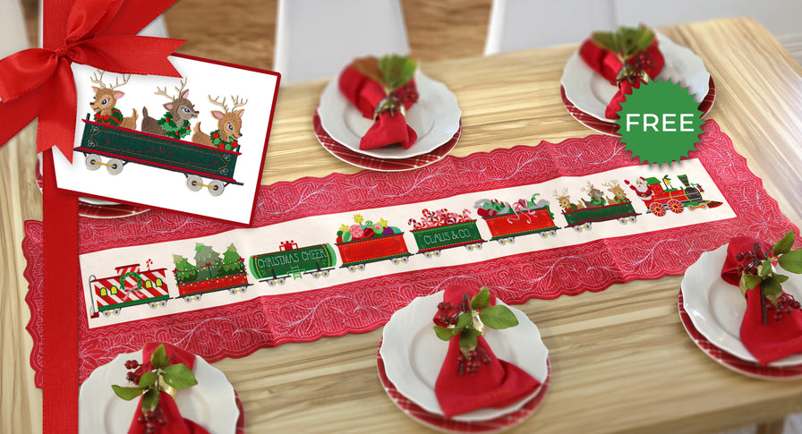 Christmas-themed table setting with a machine embroidered red train table runner on a wooden table.