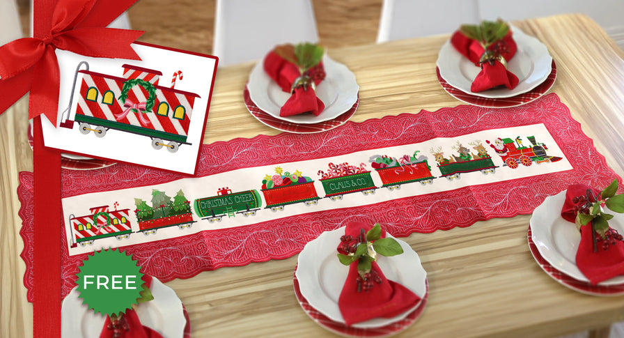 Christmas-themed table setting with a machine embroidery train design on a table runner and matching decorations on a wooden table.