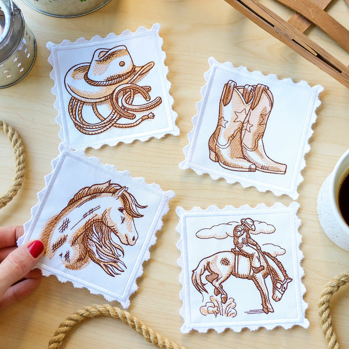 Set of machine embroidered coasters with cowboy-themed designs on a wooden table with a cup of coffee.