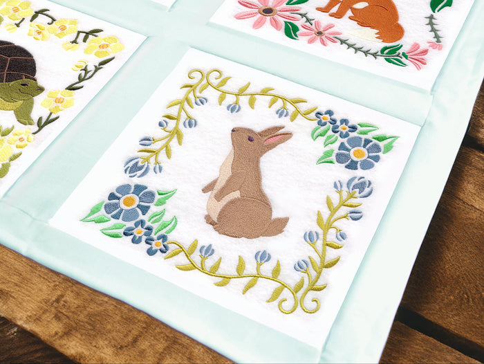 Machine embroidered fabric panels with animals and flowers on a wooden surface