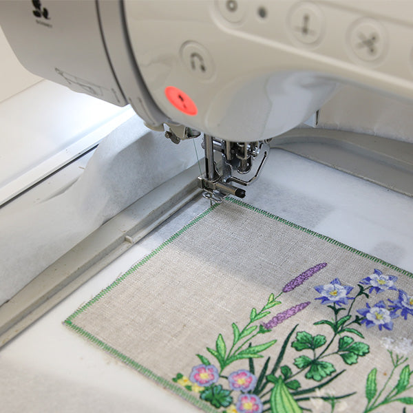 Embroidery machine stitching an embroidery floral design on a mug rug.